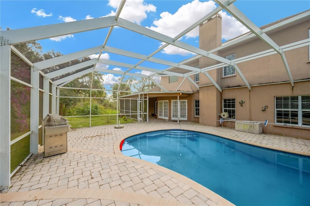 view of pool with french doors, area for grilling, a lanai, and a patio area