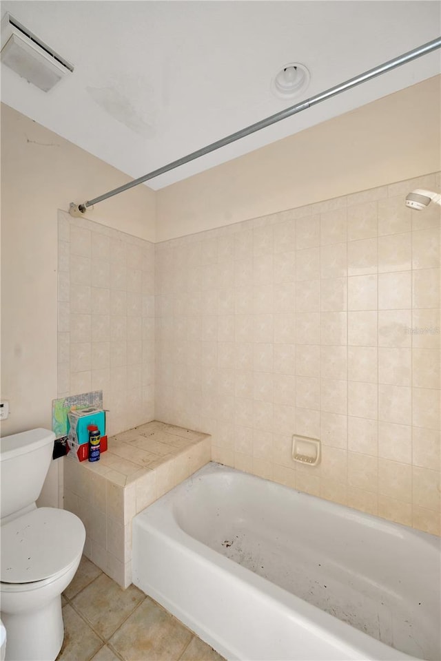 bathroom featuring tile patterned floors, toilet, and tiled shower / bath combo