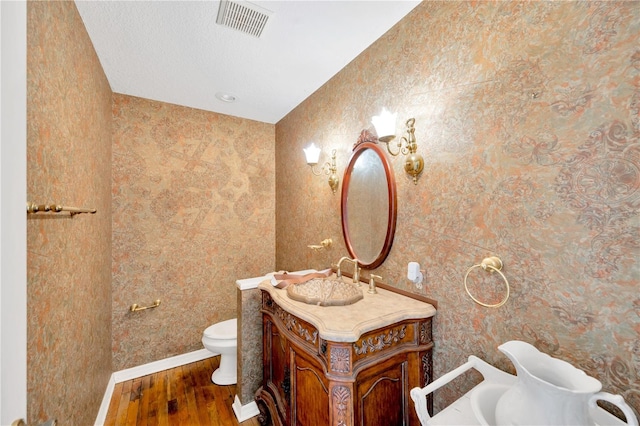 bathroom with wood-type flooring, toilet, and vanity