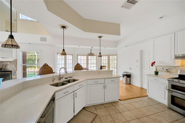 kitchen with sink, light tile patterned floors, appliances with stainless steel finishes, a tile fireplace, and white cabinets