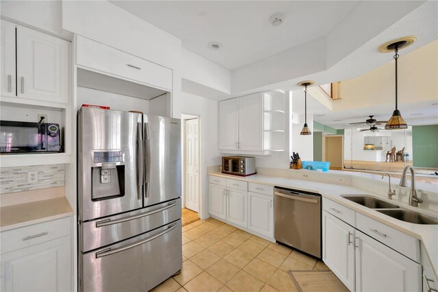 kitchen with light tile patterned flooring, sink, white cabinets, hanging light fixtures, and stainless steel appliances