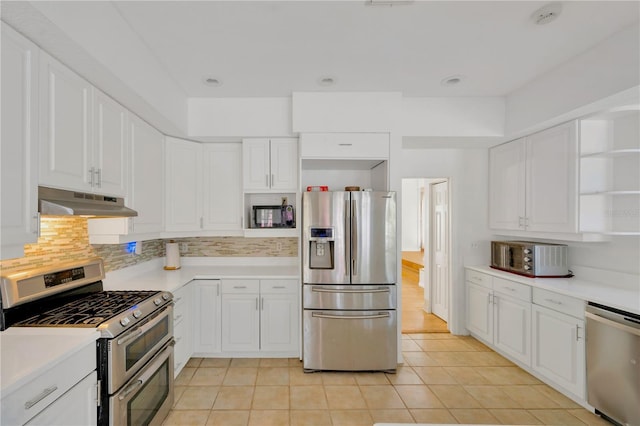 kitchen with decorative backsplash, white cabinets, and appliances with stainless steel finishes