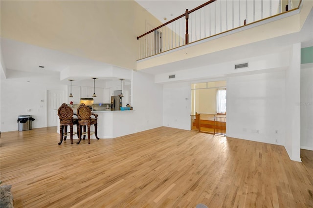 living room with a towering ceiling and light hardwood / wood-style flooring