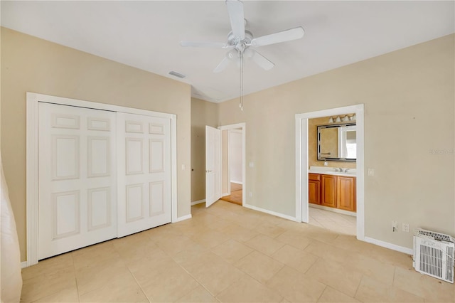 unfurnished bedroom featuring connected bathroom, sink, light tile patterned floors, a closet, and ceiling fan