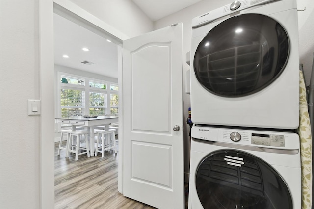 laundry area featuring stacked washer and clothes dryer and light wood-type flooring