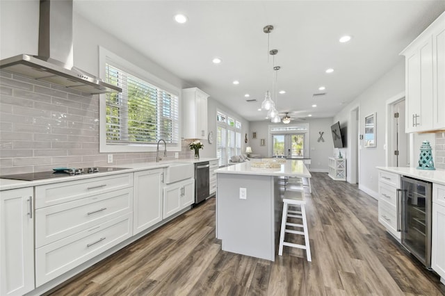 kitchen featuring white cabinetry, wall chimney range hood, beverage cooler, and a kitchen island