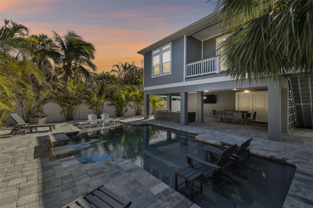 pool at dusk with an outdoor living space and a patio area