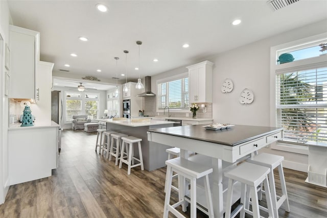 kitchen with white cabinetry, hanging light fixtures, dark hardwood / wood-style floors, a center island, and tasteful backsplash