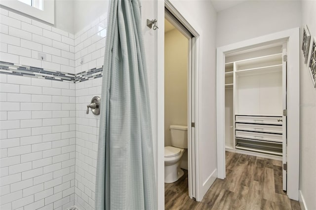 bathroom featuring hardwood / wood-style floors, toilet, and walk in shower