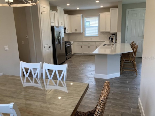 kitchen with sink, a breakfast bar area, stainless steel appliances, and white cabinets