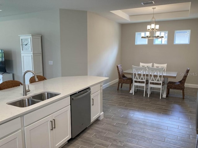 kitchen with pendant lighting, sink, white cabinetry, stainless steel dishwasher, and a raised ceiling