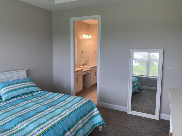 bedroom with dark colored carpet, ensuite bathroom, and sink