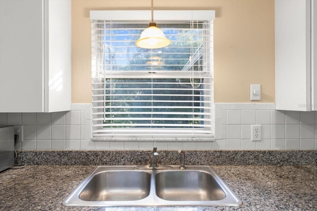 kitchen with sink, backsplash, white cabinetry, and pendant lighting