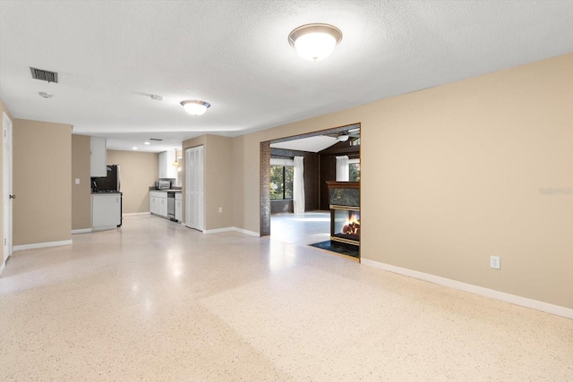 unfurnished living room featuring a multi sided fireplace and a textured ceiling