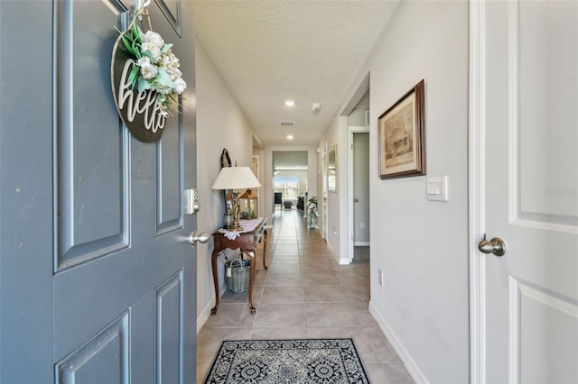 entrance foyer with a textured ceiling, light tile patterned floors, recessed lighting, and baseboards