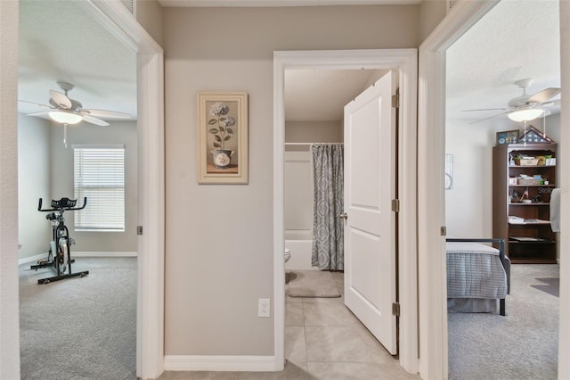 hall featuring light tile patterned flooring, baseboards, and light colored carpet