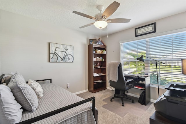 bedroom featuring a textured ceiling, baseboards, a ceiling fan, and light colored carpet