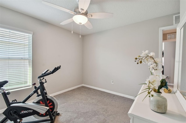 workout room with a textured ceiling, carpet flooring, a ceiling fan, and baseboards