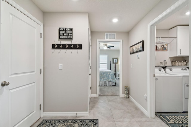 laundry area with washing machine and clothes dryer, light tile patterned floors, visible vents, cabinet space, and baseboards