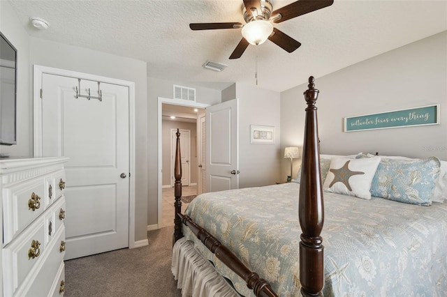 bedroom with a textured ceiling, dark carpet, visible vents, and a ceiling fan