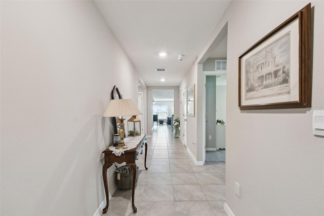 hallway with light tile patterned floors, visible vents, and baseboards