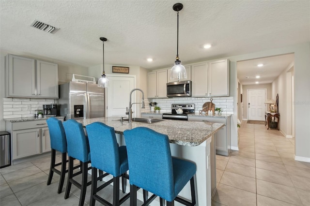 kitchen featuring light tile patterned floors, appliances with stainless steel finishes, a sink, and visible vents