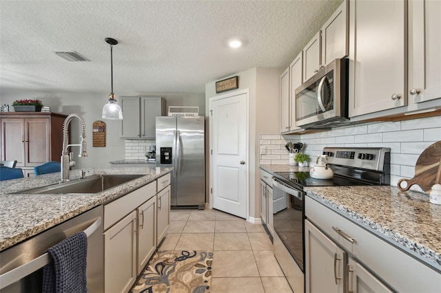 kitchen featuring light tile patterned floors, a sink, visible vents, appliances with stainless steel finishes, and decorative light fixtures