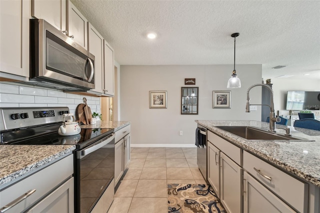 kitchen featuring light tile patterned floors, stainless steel appliances, a sink, hanging light fixtures, and tasteful backsplash