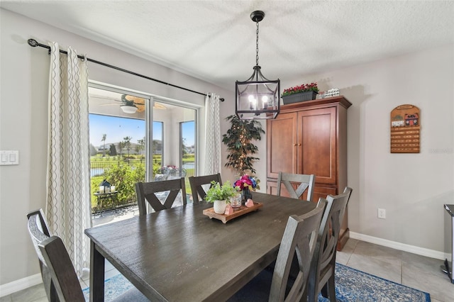 dining area featuring light tile patterned floors, baseboards, and a textured ceiling