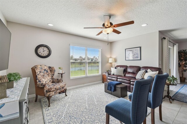 living area with light tile patterned floors, recessed lighting, a ceiling fan, a textured ceiling, and baseboards