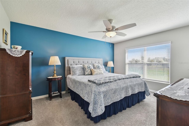 carpeted bedroom with a textured ceiling, baseboards, and a ceiling fan