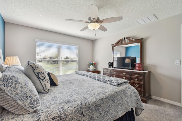 carpeted bedroom featuring baseboards, a textured ceiling, visible vents, and a ceiling fan