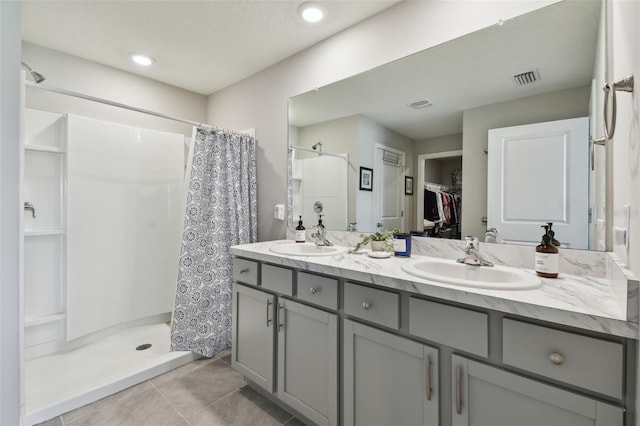 full bathroom featuring visible vents, a sink, a shower stall, and double vanity