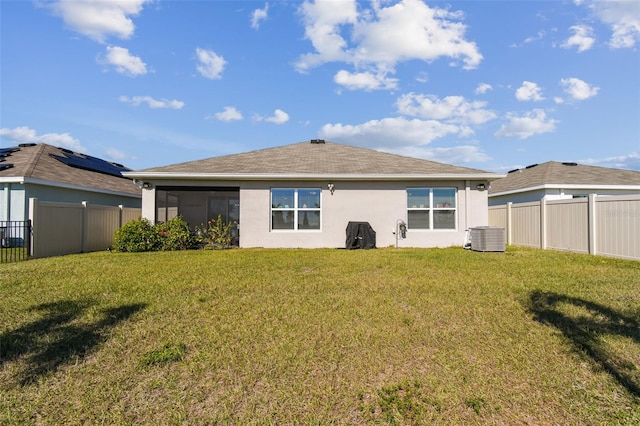 rear view of house featuring a fenced backyard, a lawn, central AC, and stucco siding