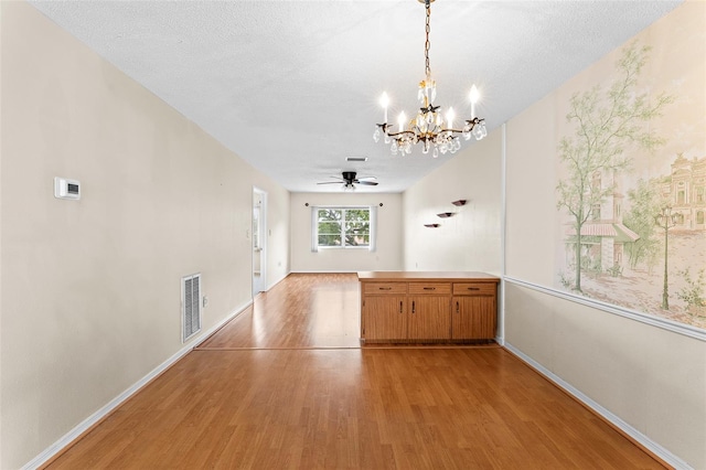 unfurnished dining area with light wood-style floors, baseboards, visible vents, and a textured ceiling