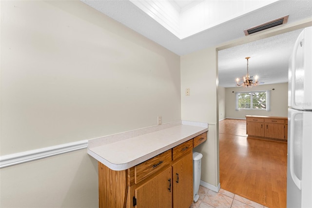 kitchen with a chandelier, visible vents, light countertops, freestanding refrigerator, and decorative light fixtures