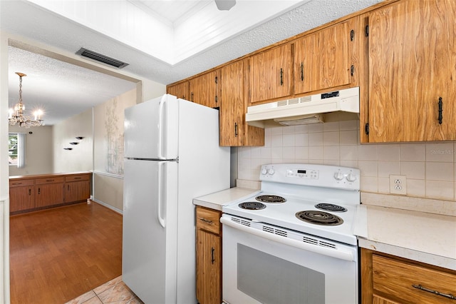 kitchen featuring light countertops, white appliances, visible vents, and under cabinet range hood