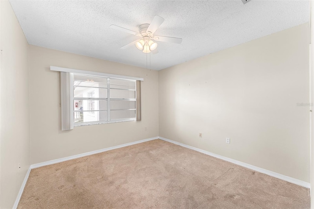 carpeted spare room with a ceiling fan, baseboards, and a textured ceiling