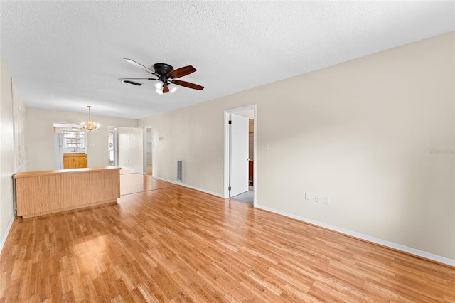 unfurnished living room with a textured ceiling, ceiling fan with notable chandelier, and light wood-style flooring