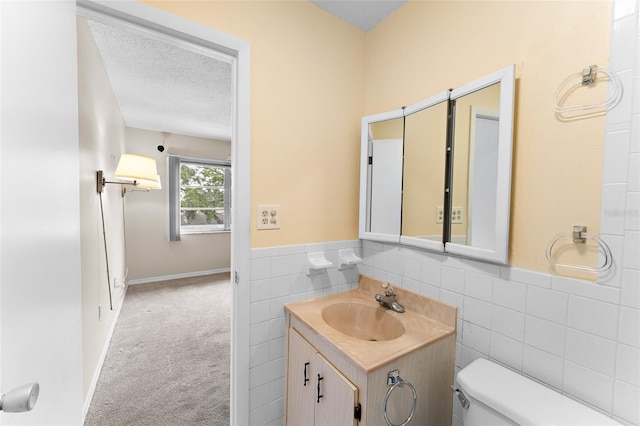 bathroom with tile walls, toilet, wainscoting, a textured ceiling, and vanity