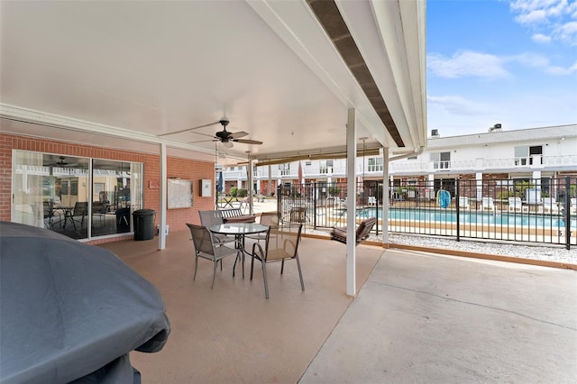 view of patio with a ceiling fan, outdoor dining area, fence, and a community pool