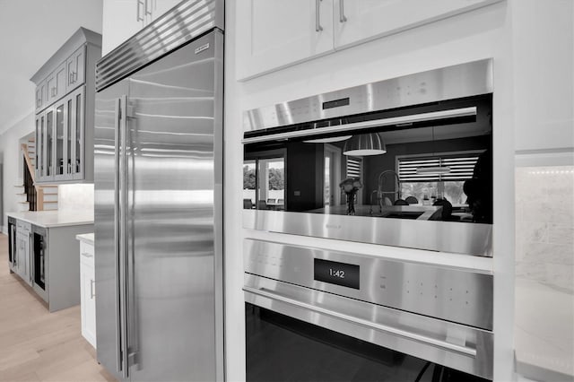 kitchen with light stone counters, gray cabinets, stainless steel appliances, and light hardwood / wood-style floors