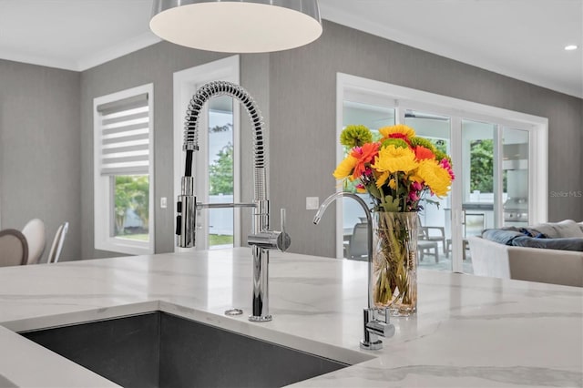 room details with light stone counters, sink, and crown molding