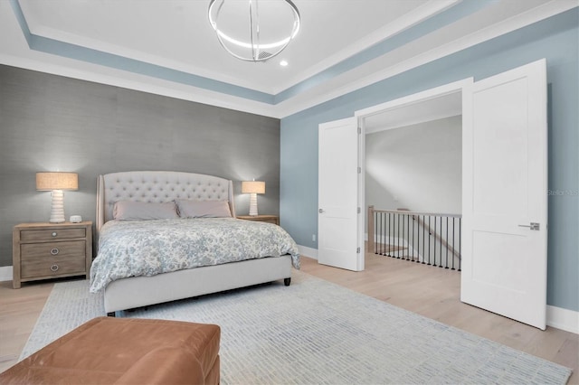 bedroom featuring a tray ceiling and light hardwood / wood-style floors