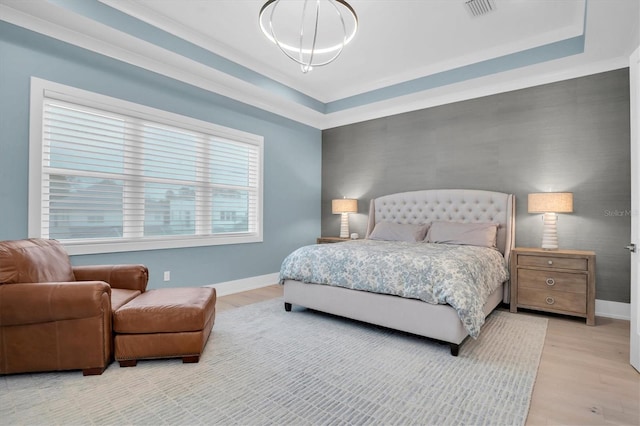 bedroom with a raised ceiling and light wood-type flooring