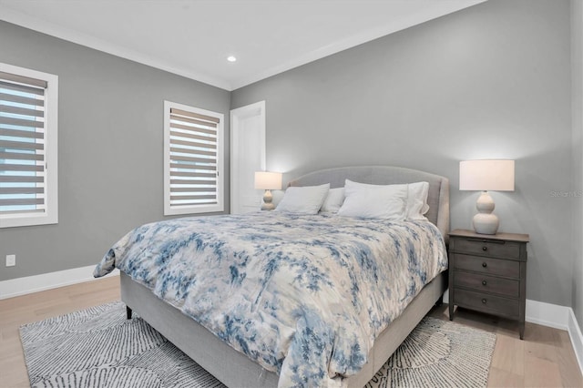 bedroom featuring crown molding, light hardwood / wood-style floors, and multiple windows