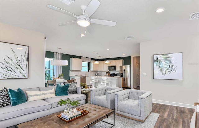 living room featuring sink, ceiling fan, and dark hardwood / wood-style flooring