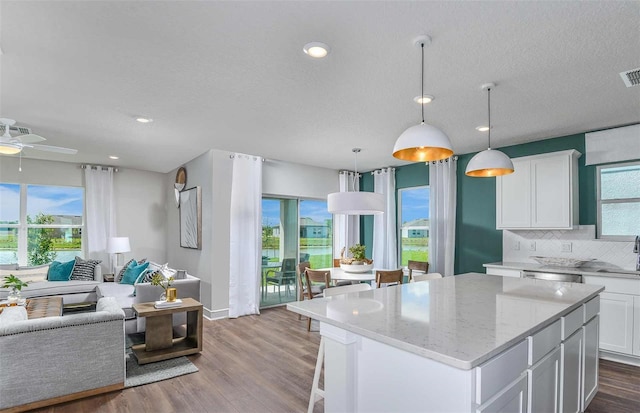 kitchen featuring a kitchen island, white cabinetry, decorative backsplash, and decorative light fixtures