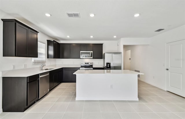 kitchen with light tile patterned flooring, a kitchen island, sink, and stainless steel appliances