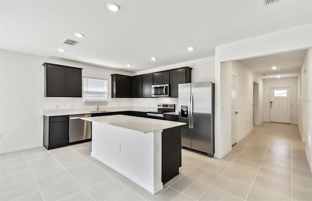 kitchen with light tile patterned flooring, a center island, appliances with stainless steel finishes, and sink